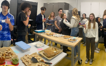 Students gathered around food they brought in for their potluck