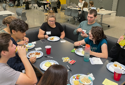 Students sitting around the table enjoying food.