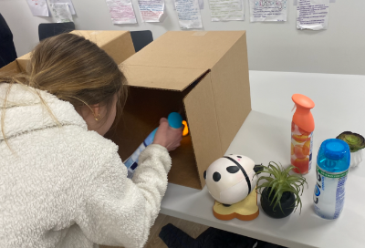 Student spraying Fabreeze into a box for her installation 