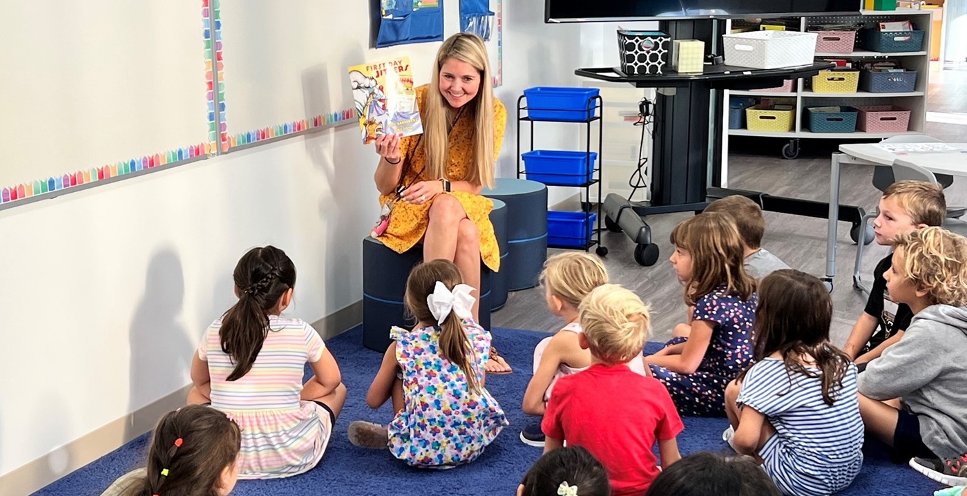 An elementary teacher reading a first day of school book to her class