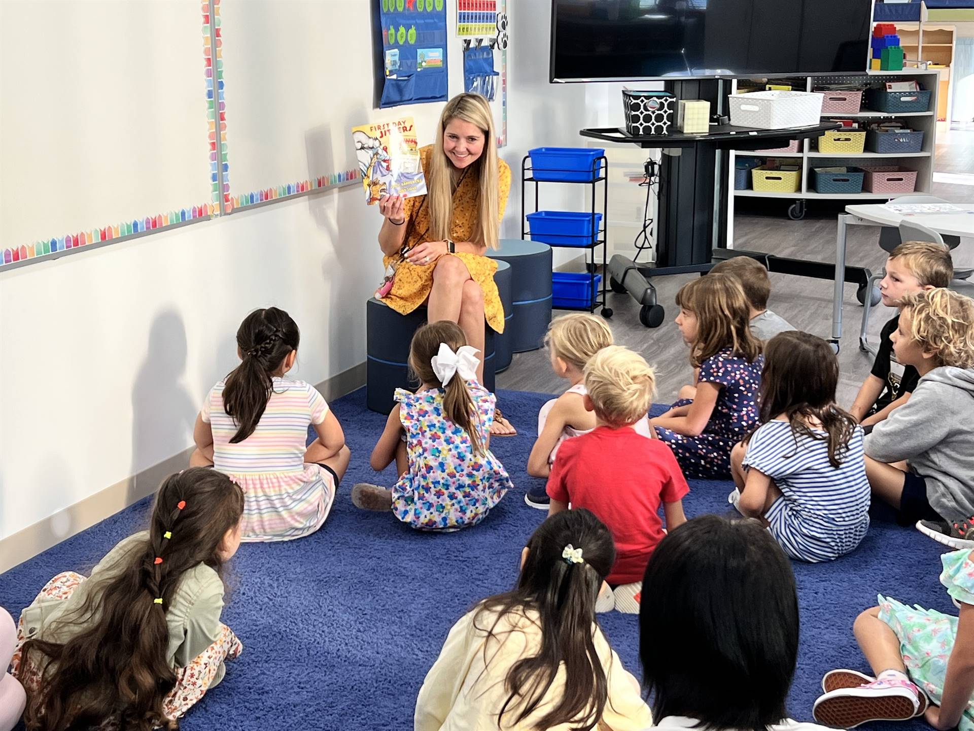 A kindergarten teacher reading to her students a book called "First Day Jitters" on the first day of