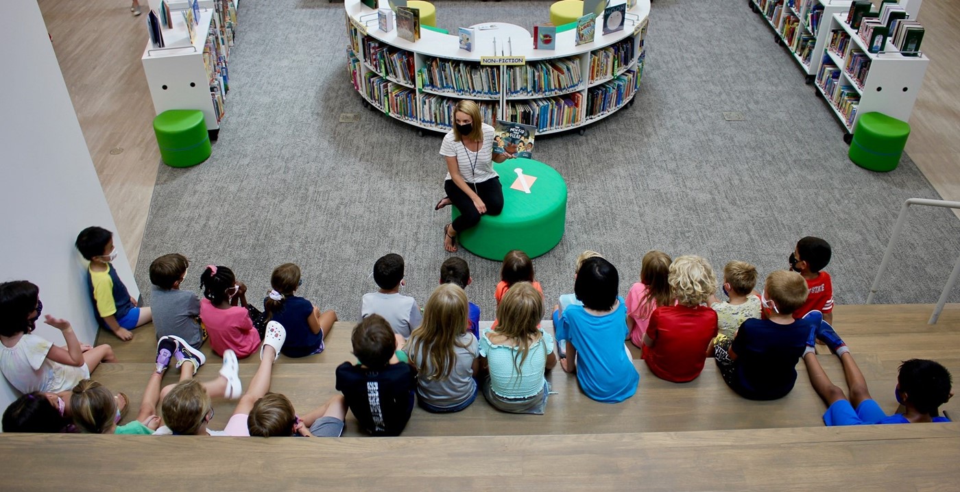 An elementary teacher reading to students on the learning stairs