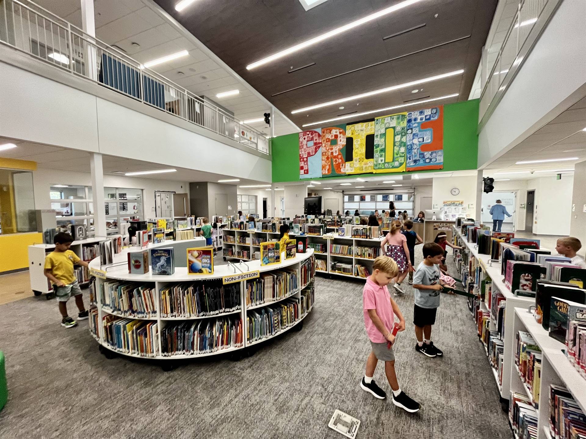 An image of the media center, with shelves of books and children perusing the shelves
