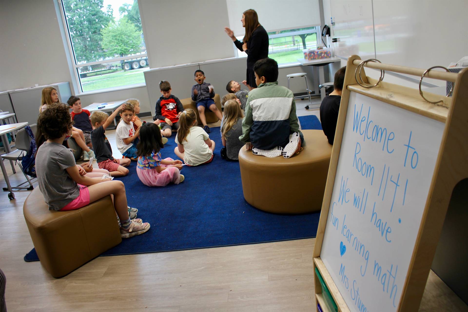 Students gathering around a carpet listening to a teacher in a Summer Academy math class