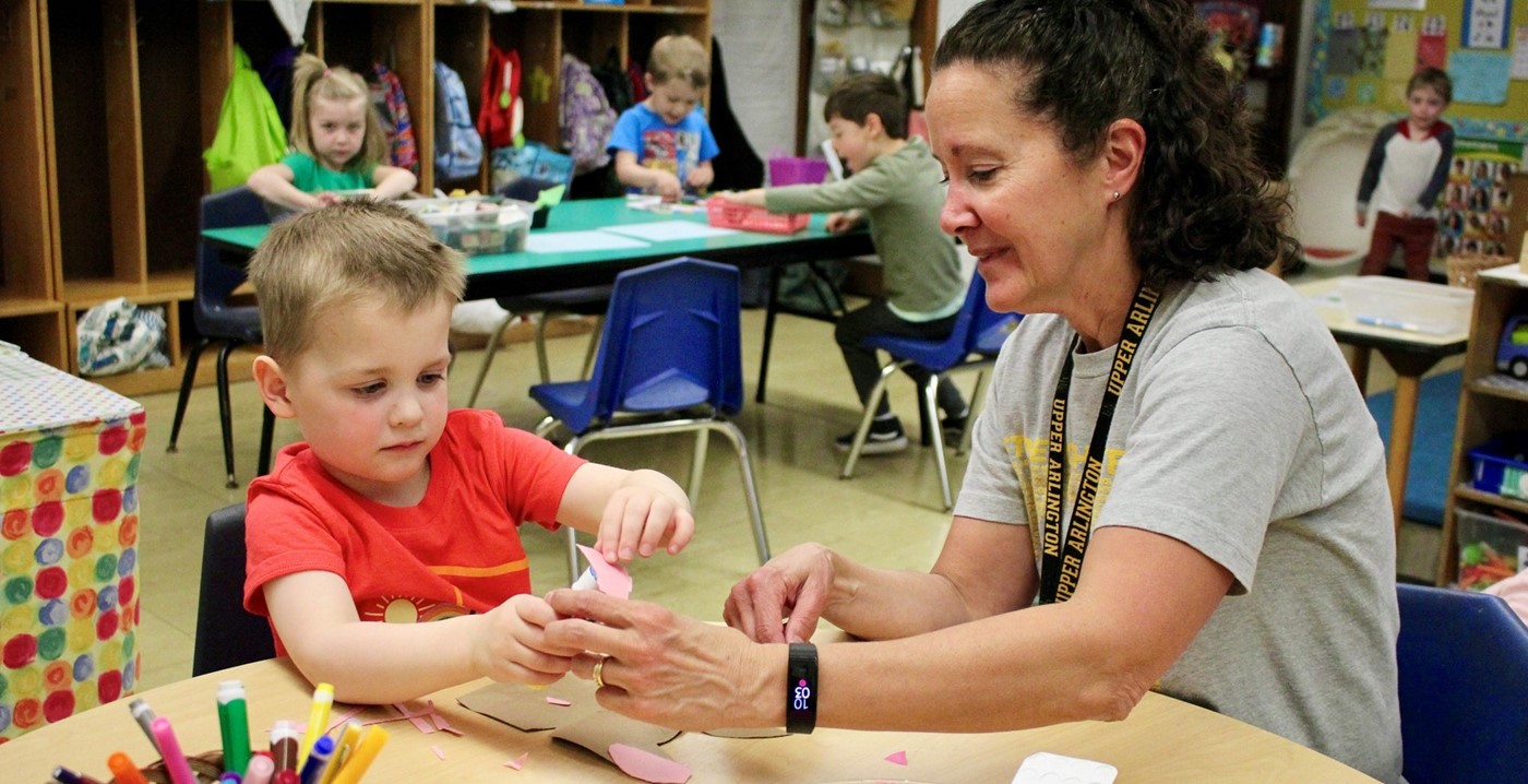 A teacher helping a student with a craft project