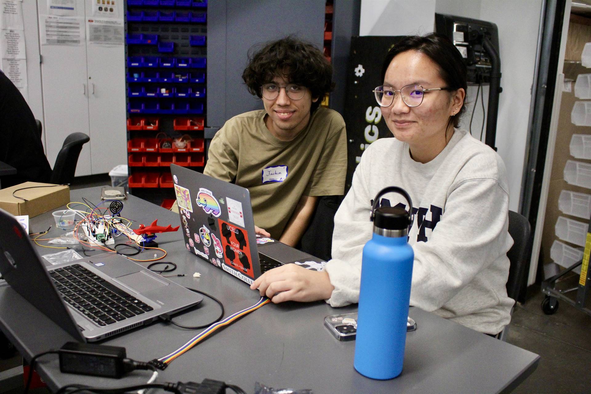 Two students smiling for a photo while engaging in a hackathon to code a game