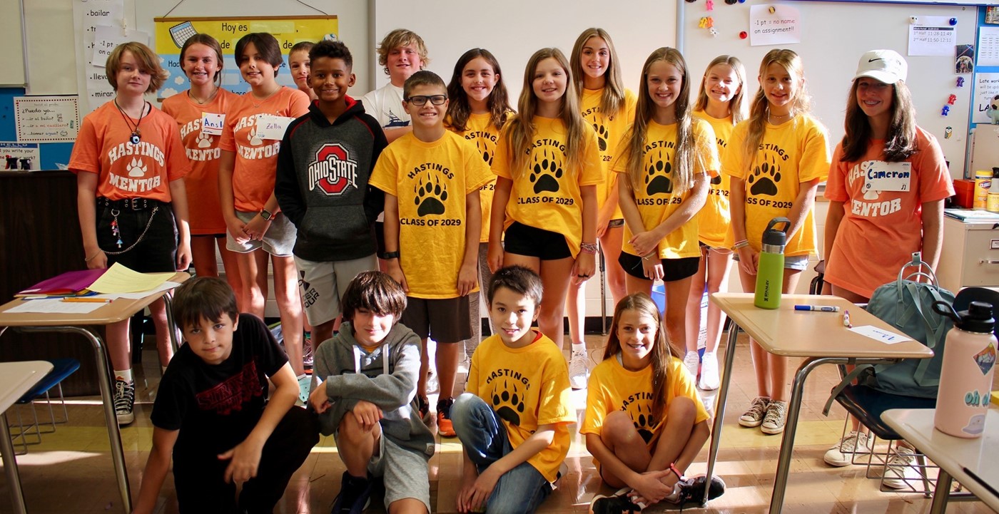 New 6th grade students and mentors posing on the first day of school in a classroom