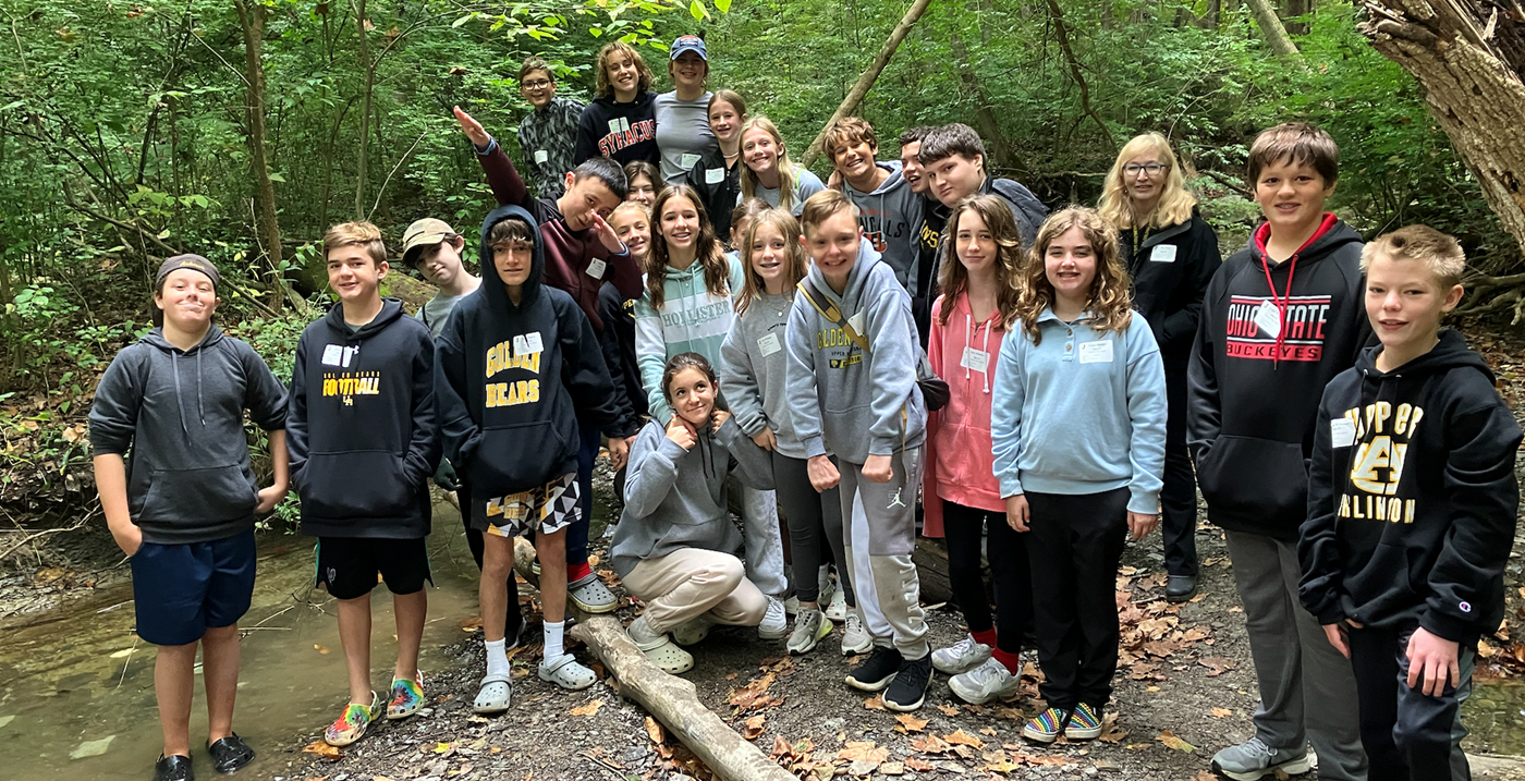 A group of students posing for a photo along a creek at Highbanks Metro Park