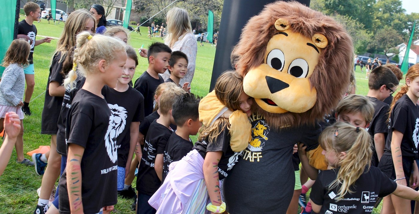 The Greensview Lion mascot hugging students during a walkathon