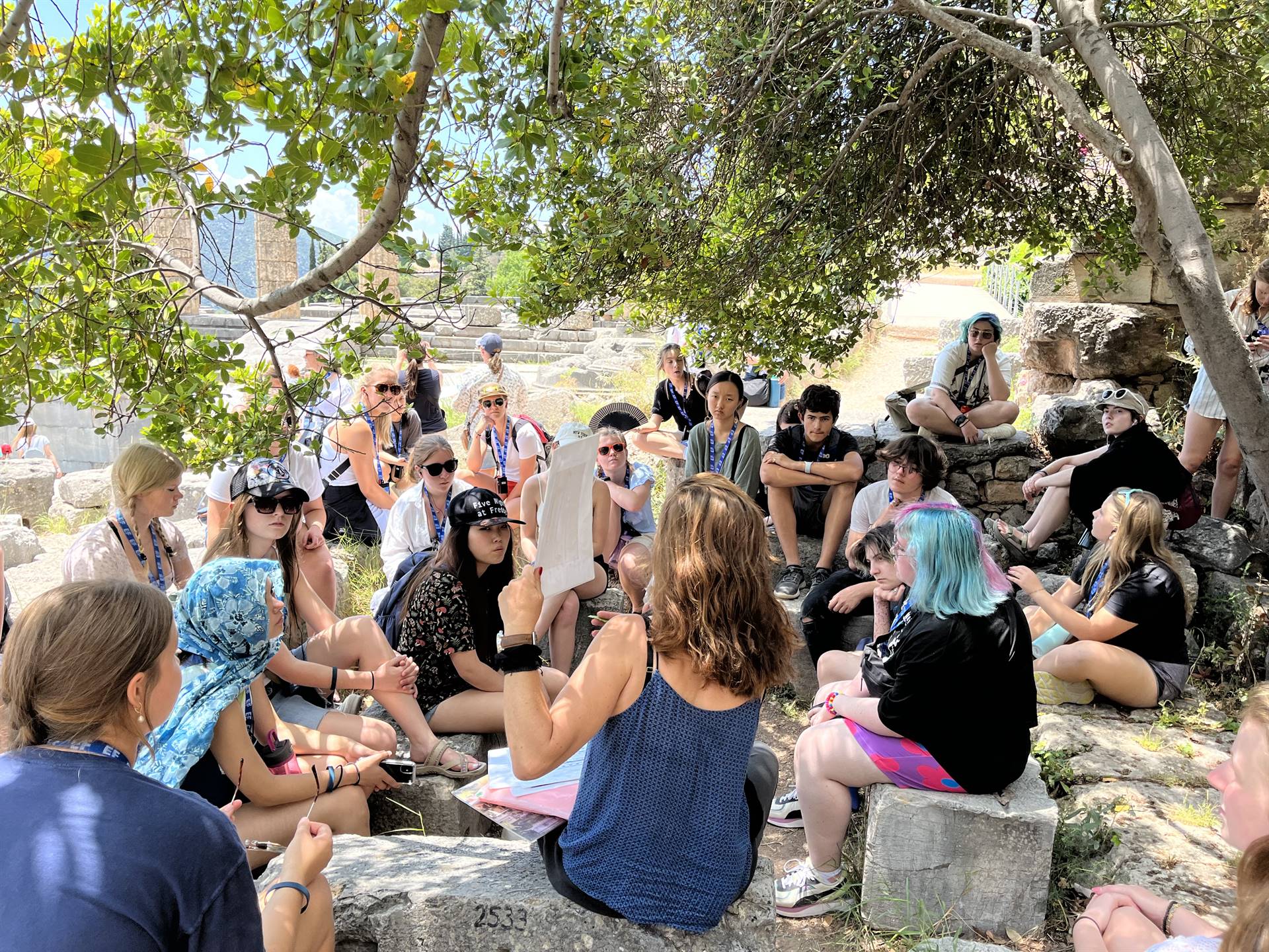A group of students gathered on rocks, listening to a speaker